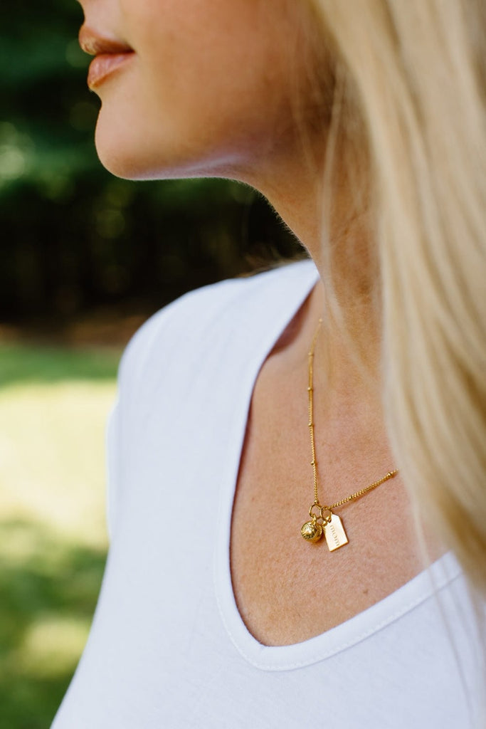 woman wearing baseball mom gold charm necklace by Chelsea Charles