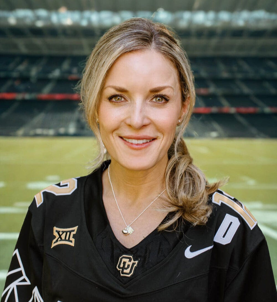 Mom in a football jersey wearing a silver football mom charm necklace 