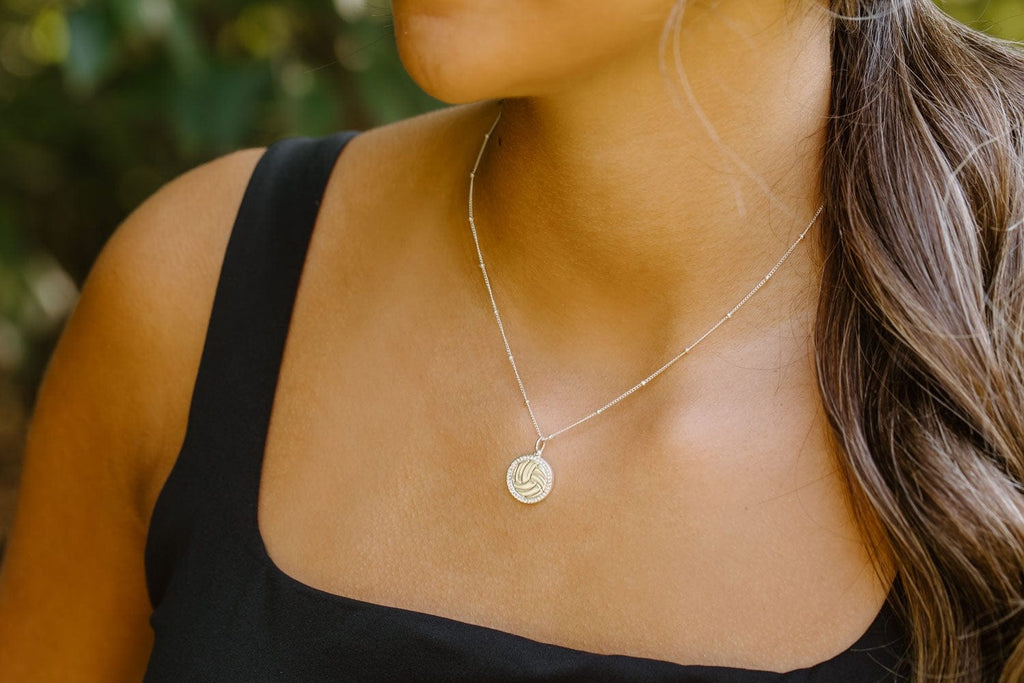 Close up of model wearing silver pave volleyball necklace