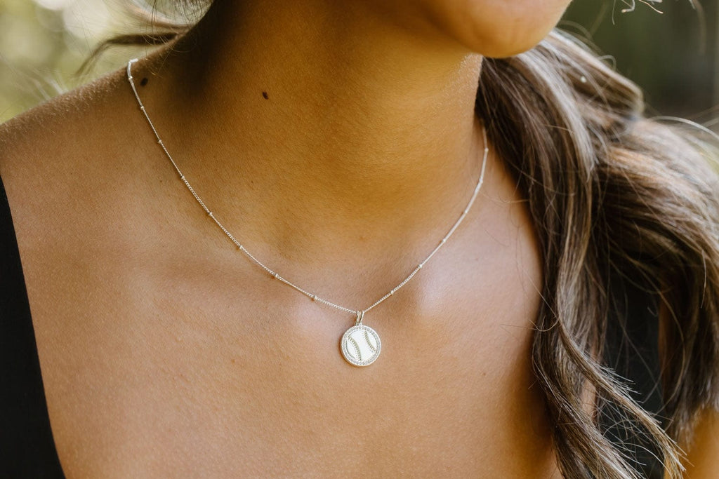 Close-up of Chelsea Charles silver softball necklace on model