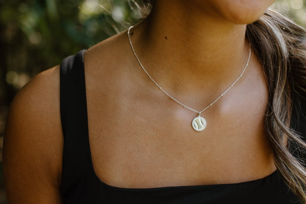 Close-up of Chelsea Charles silver softball necklace with pavé crystals on model