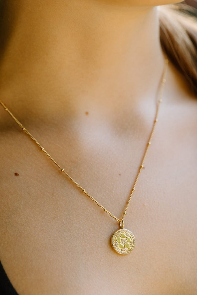 gold and crystal soccer necklace on model's neck by Chelsea Charles
