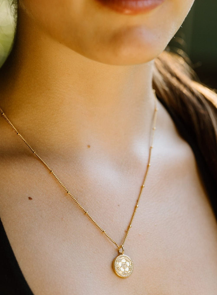 Close up of gold pavé crystal soccer necklace by Chelsea Charles